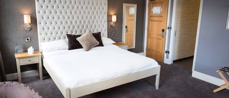 A neatly arranged bedroom with a large bed, bedside tables, and a chair.