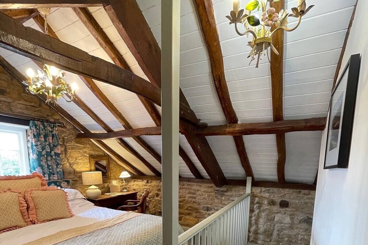 A bedroom with a bed, a desk, and a chandelier.