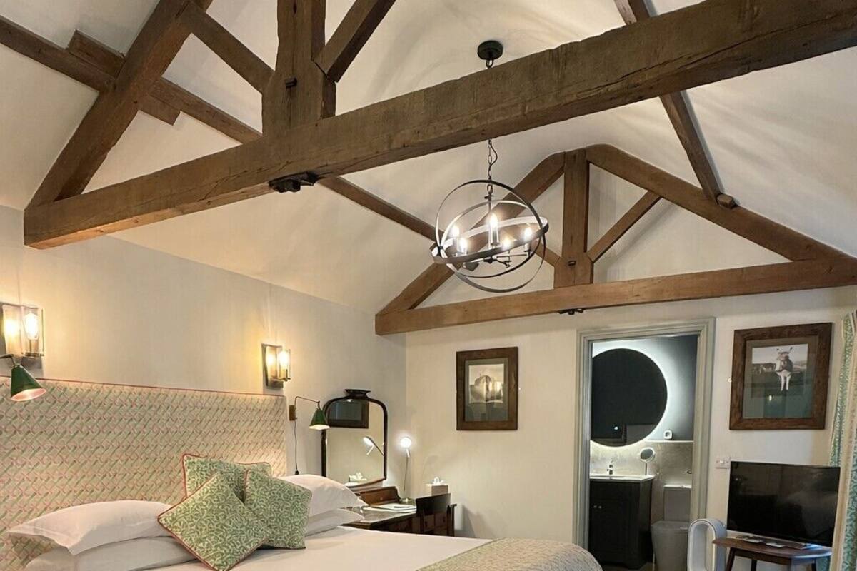 A bedroom with a large bed, a desk, a mirror, and a chandelier.