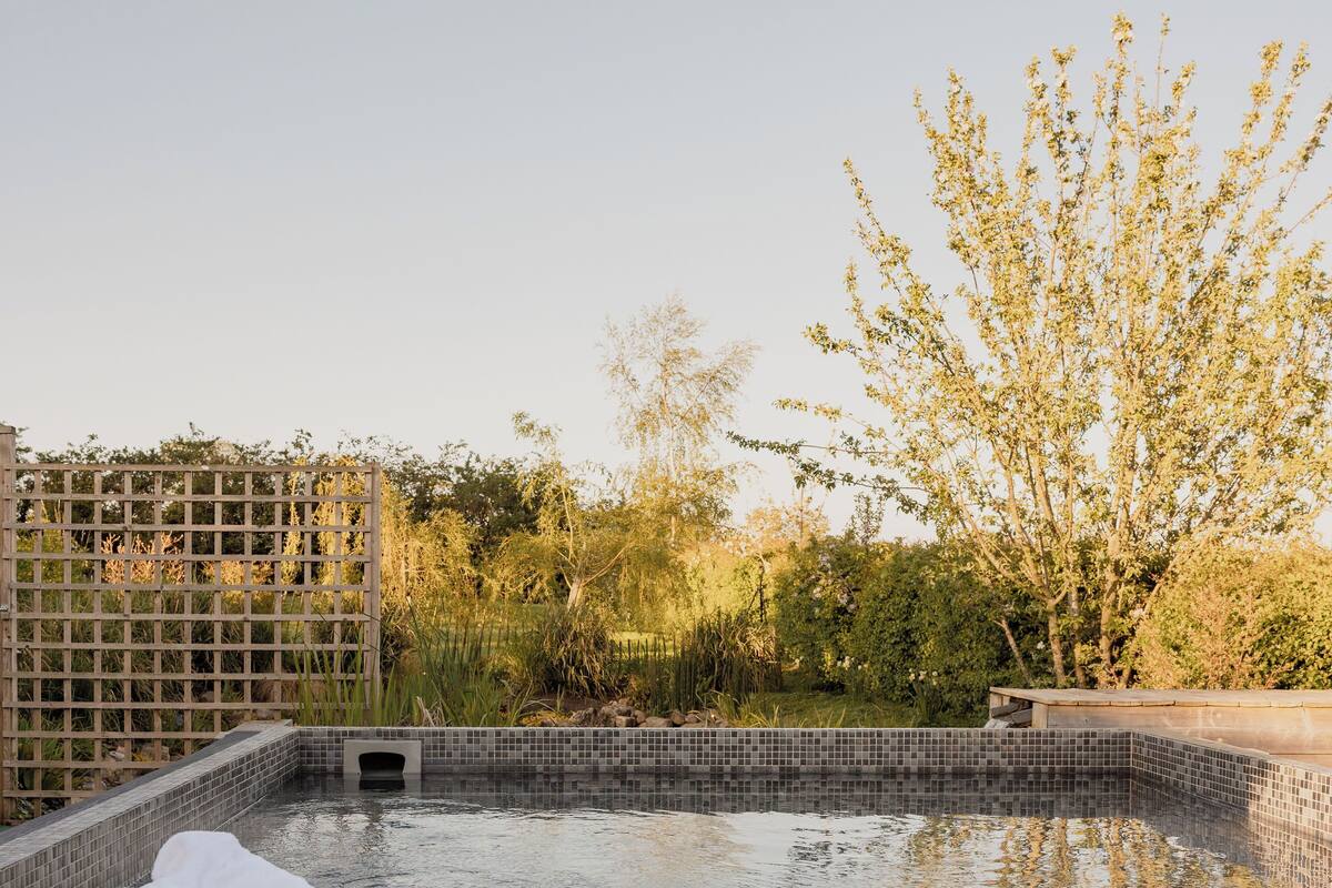 A wooden deck with a hot tub, a bench, and a towel.