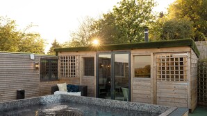 A wooden cabin with a glass door, a small pool, and a patio area. - The Durham Ox (York)