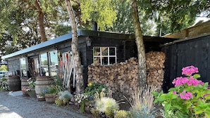 A rustic building with a wooden exterior, a stack of firewood, and various potted plants. - The Durham Ox (York)