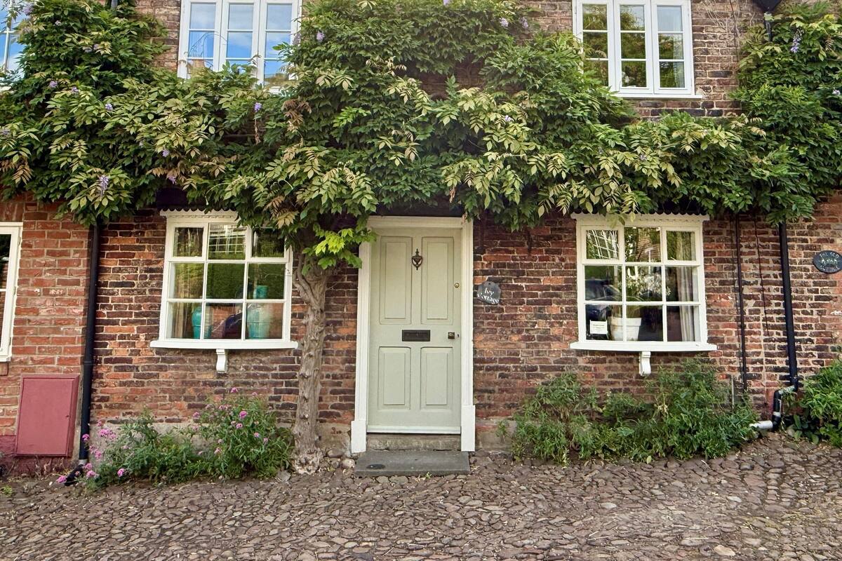 A brick house with a tiled roof, a white door, and windows with white frames.