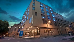 Un hotel moderno con una entrada destacada y un letrero que indica un área de estacionamiento.