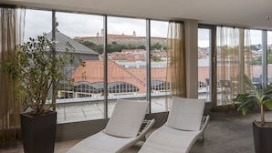 Un balcón con dos sillones, una planta en maceta y vistas a un edificio histórico.