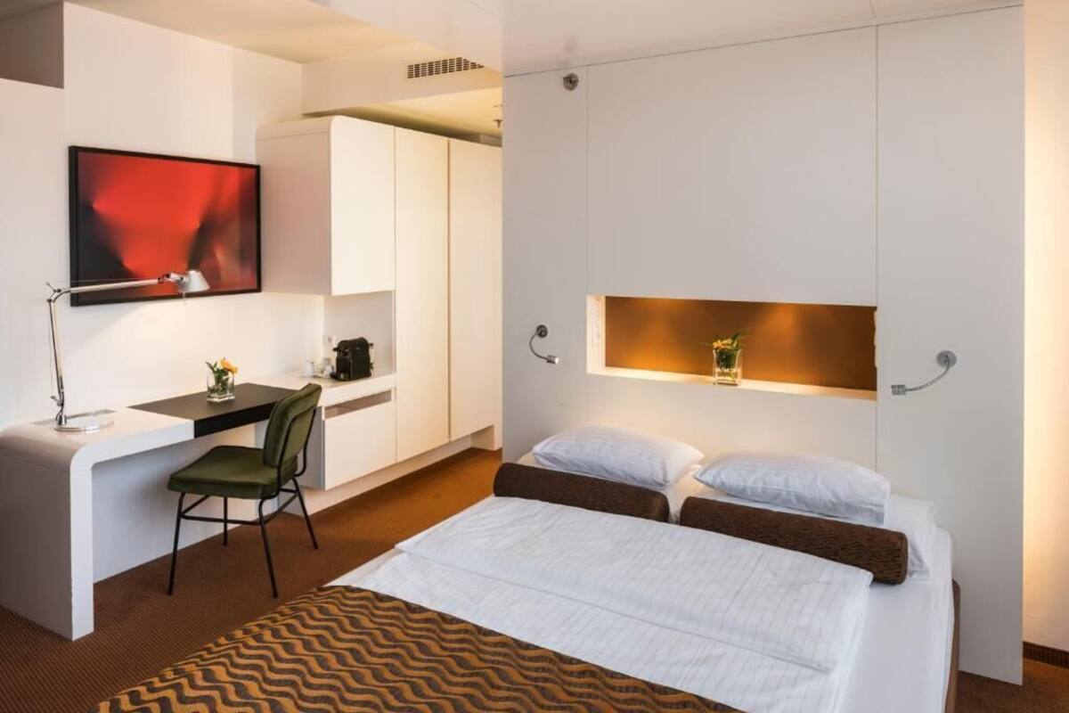 Une chambre d’hôtel moderne équipée d’un lit, d’un bureau et d’une télévision.