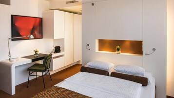 Une chambre d’hôtel moderne équipée d’un lit, d’un bureau et d’une télévision.