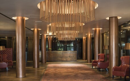 A lobby with a reception desk, large cylindrical columns, and leather armchairs.
