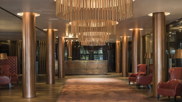 Un vestíbulo con mostrador de recepción, grandes columnas cilíndricas y sillones de cuero.