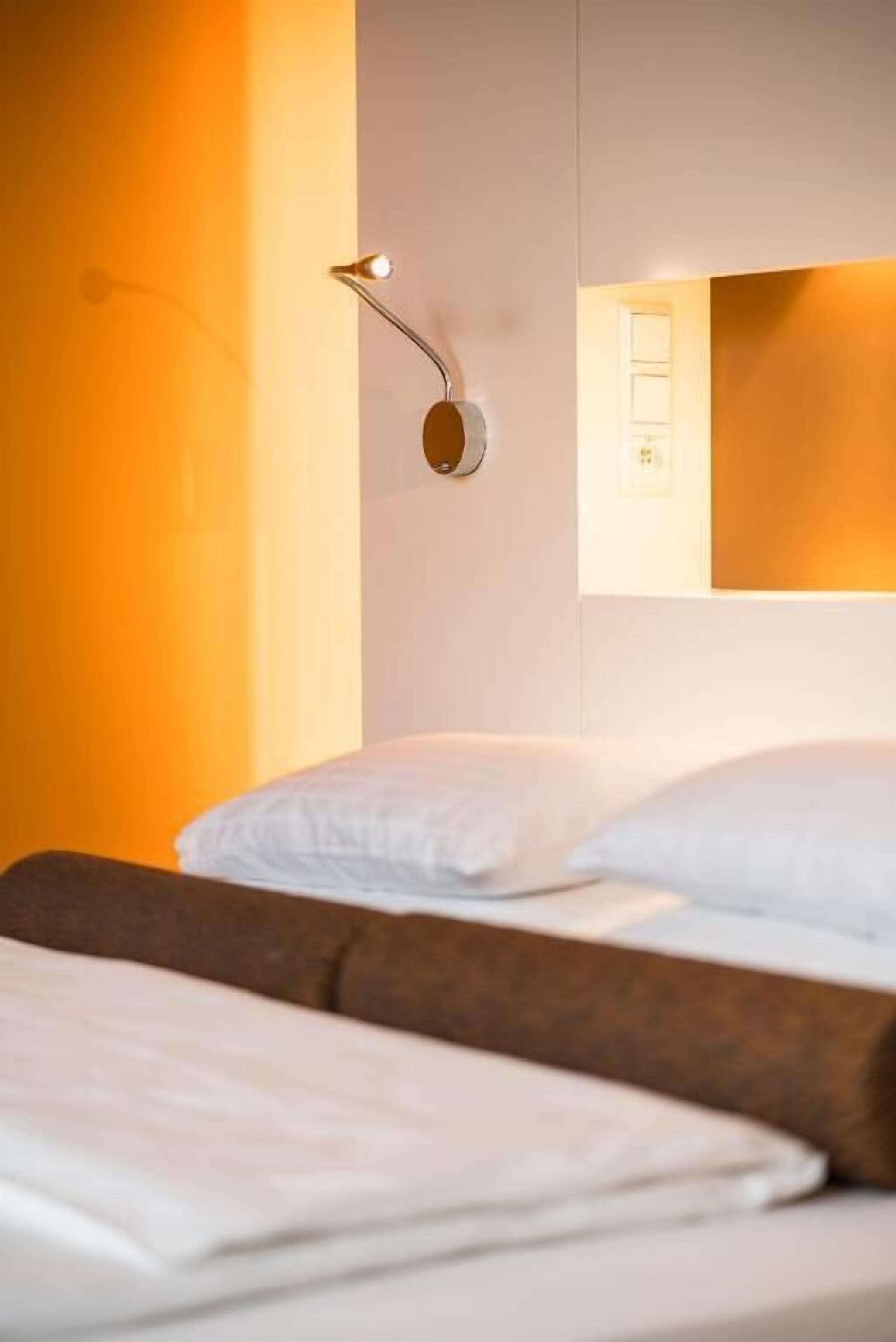 Ein Hotelzimmer mit Bett, Wandlampe und Spiegel.