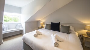 Une chambre à coucher avec un grand lit, un coin fenêtre aménagé en siège et deux lampes de chevet.