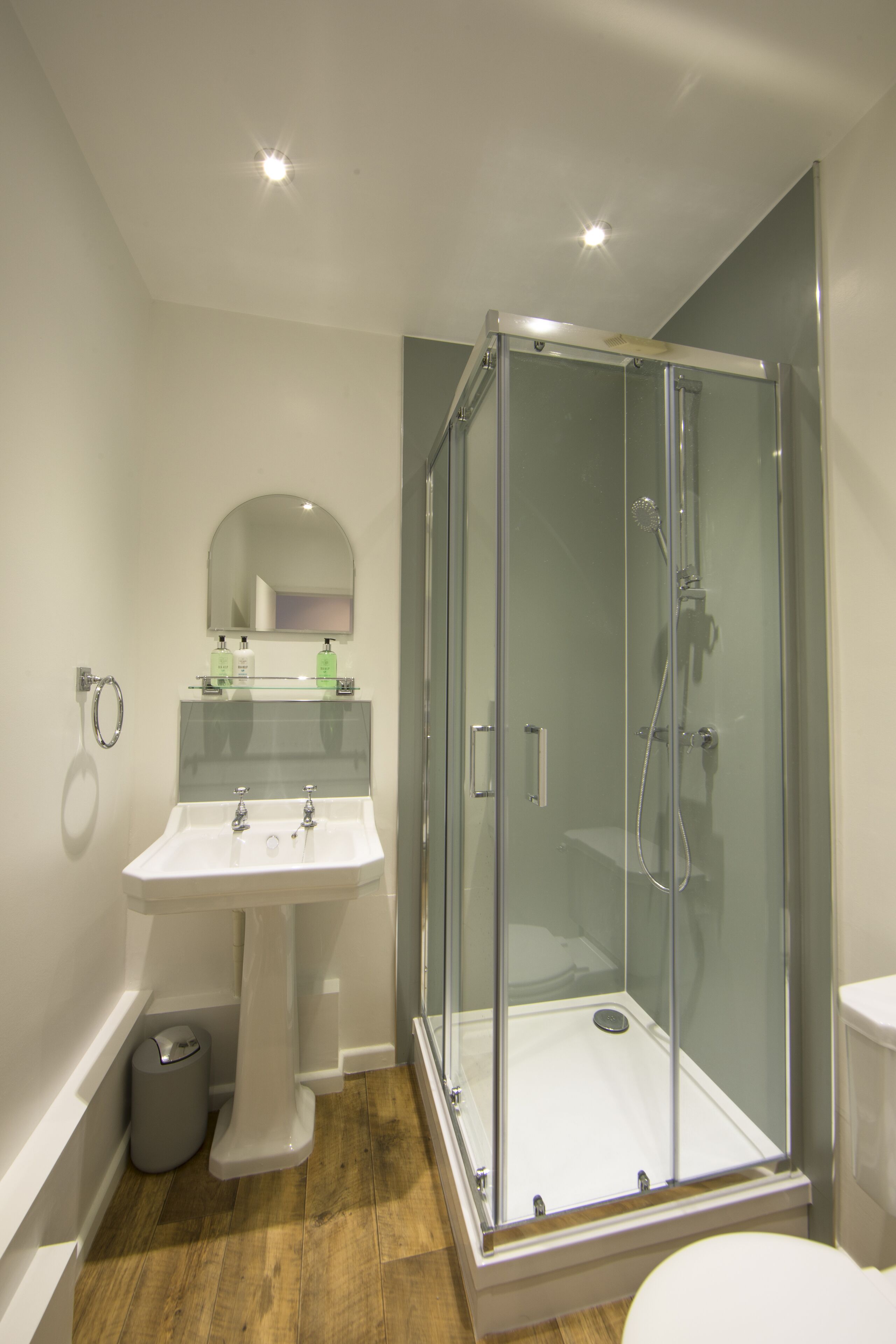 Une salle de bain moderne avec une douche à parois de verre, un lavabo sur colonne et des toilettes.