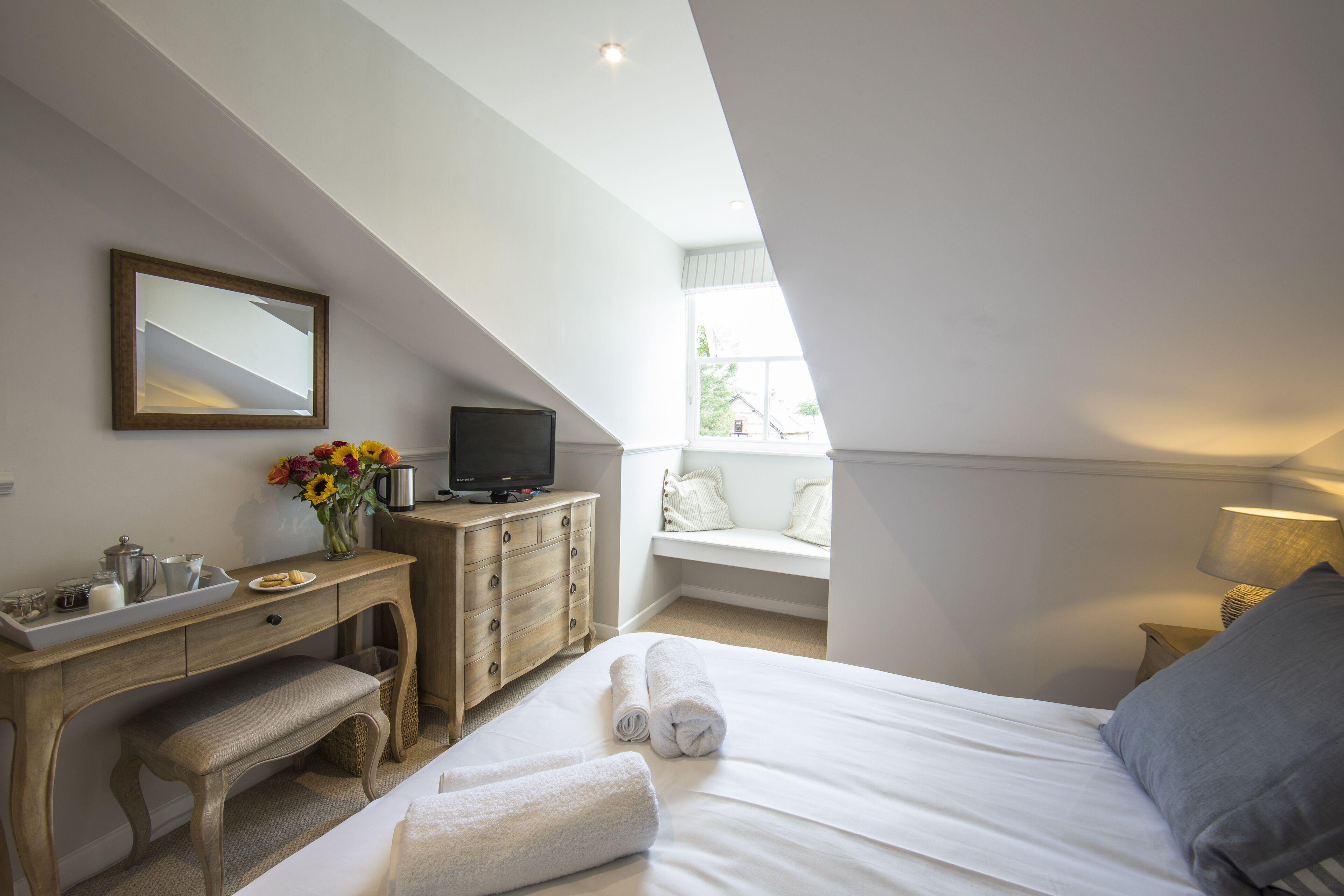 Un dormitorio con cama, escritorio, televisión y ventana con vistas.