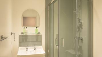 A bathroom with a glass-enclosed shower, a sink, and a mirror above it.