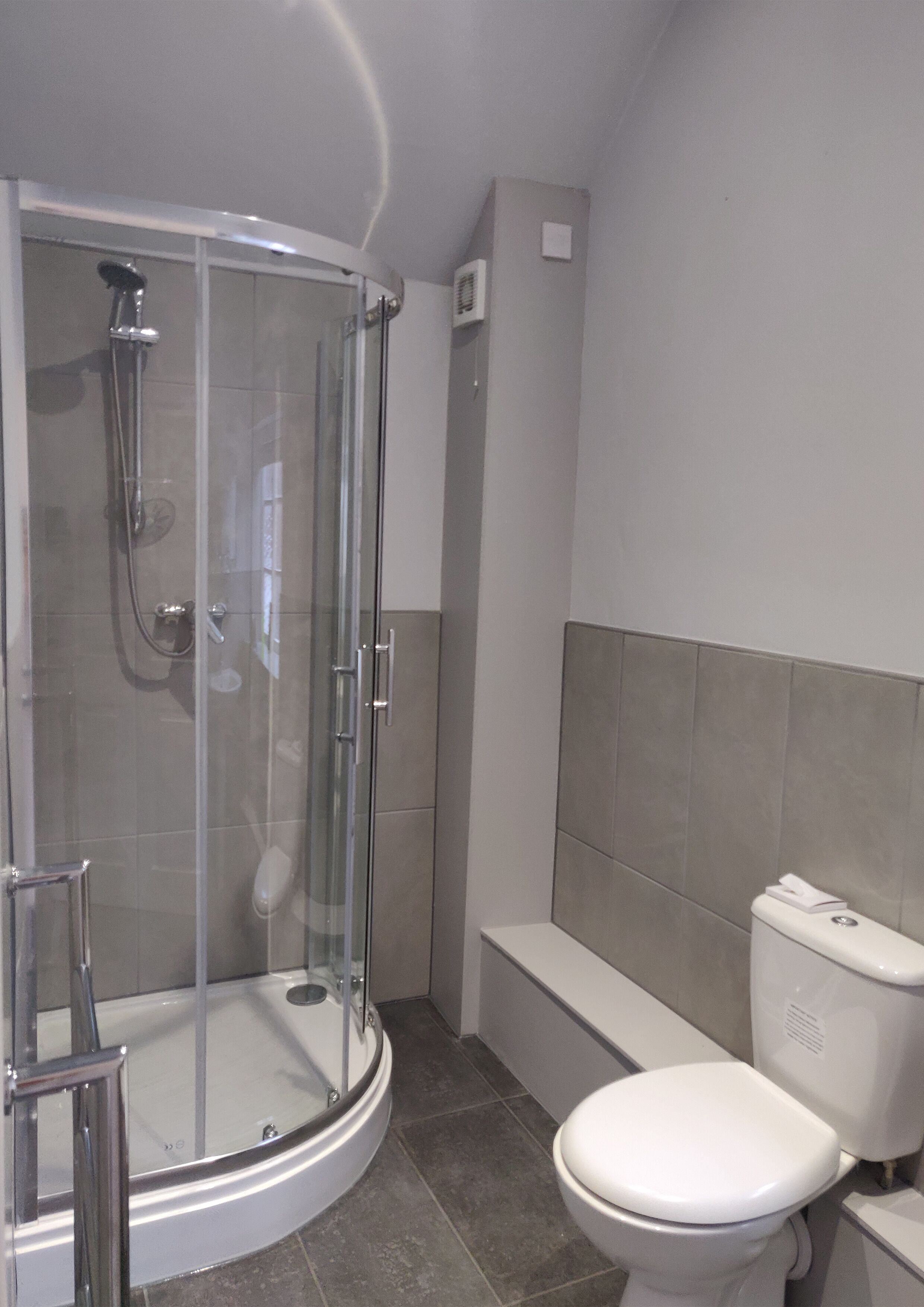 A modern bathroom with a glass-enclosed shower, a white toilet, and a bathtub.