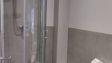A modern bathroom with a glass-enclosed shower, a white toilet, and a bathtub.