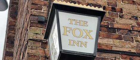 A brick building with a sign that reads "The Fox Inn".
