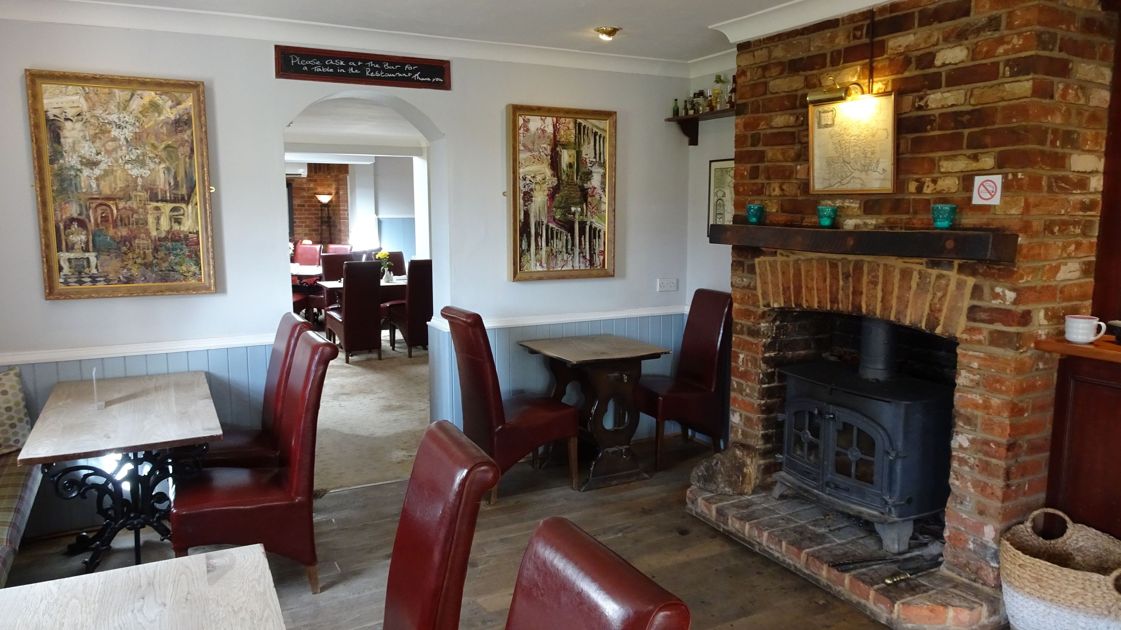 A cozy restaurant interior with brick fireplace, wooden tables, and red leather booths.