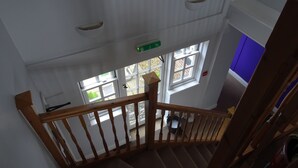 Una escalera de madera con barandilla que conduce a un rellano con ventana.