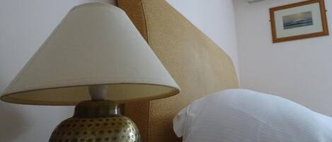 A room with a bed, a lamp, a wall-mounted air conditioner, and a framed picture.