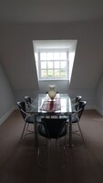 Un comedor con mesa de vidrio, sillas negras y un jarrón como centro de mesa.