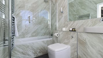 A modern bathroom with a glass shower enclosure, a white toilet, and a marble backsplash.