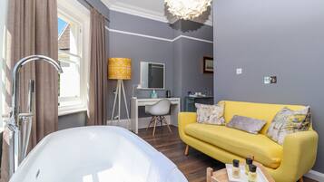 A modern bathroom with a bathtub, a yellow sofa, and a desk with a lamp.