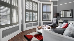 Una sala de estar moderna con ventanas amplias, un sofá gris, una mesa de centro y una lámpara.