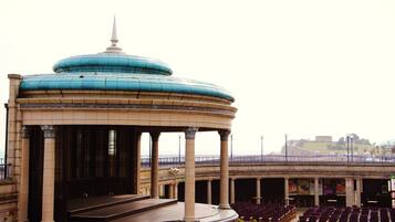 A large, open-air auditorium with tiered seating and a central stage, surrounded by columns and a dome structure.