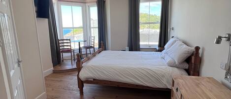 Un dormitorio con una cama de madera, un tocador de madera, un televisor y vistas al exterior.