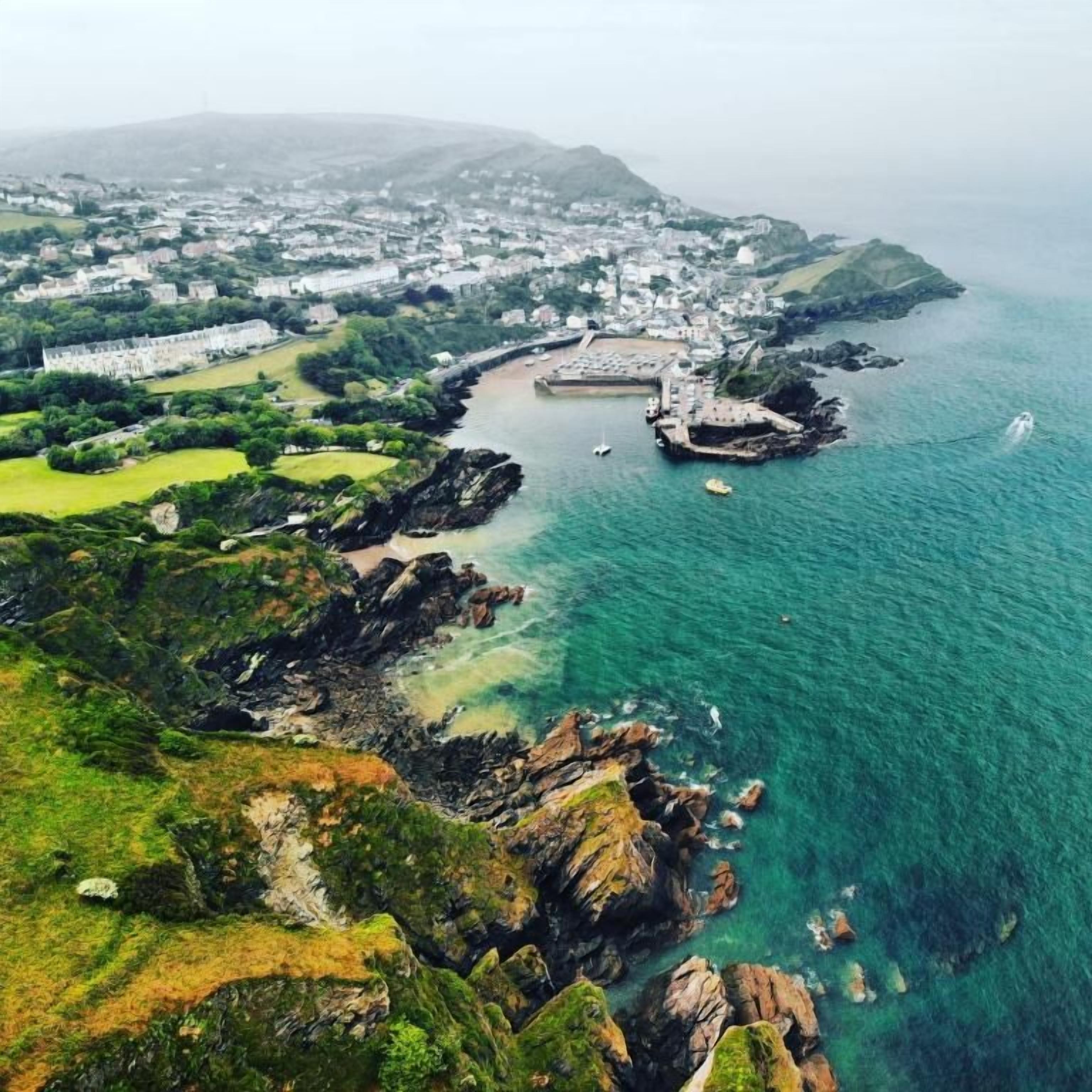 A coastal town with a marina, rocky shoreline, and buildings along the water.