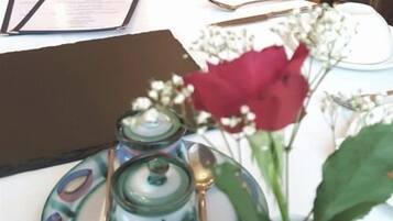 A table with a menu, a vase with a red flower, and a small green container.