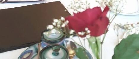A table with a menu, a vase with a red flower, and a small green container.