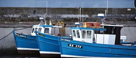 Two boats docked at a pier with a rocky shoreline in the background.