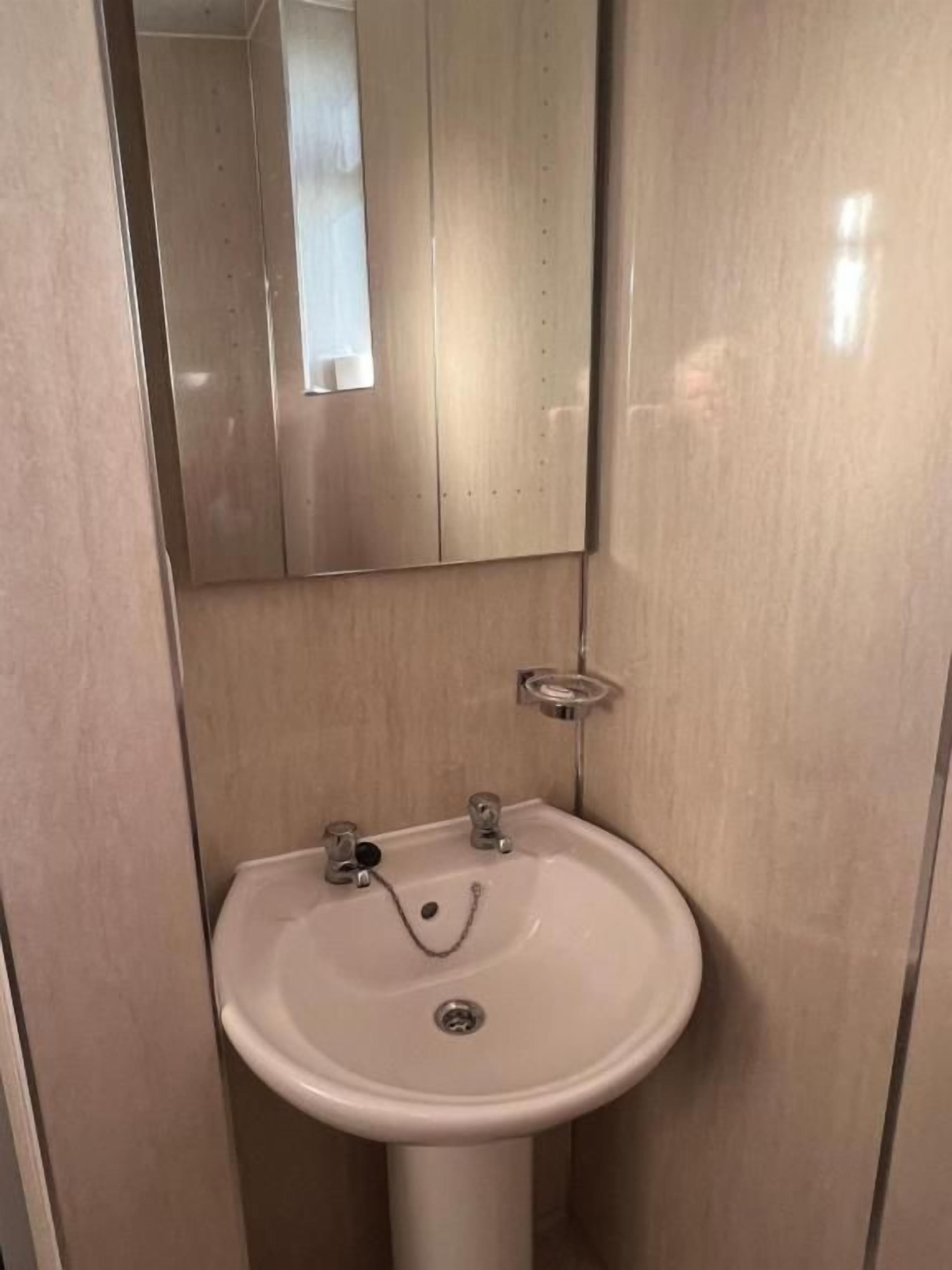 A bathroom with a white sink, a mirror, and a towel rack.
