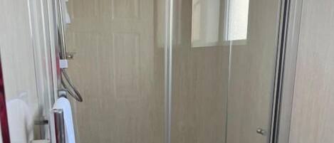 A glass-enclosed shower stall with a showerhead and a towel rack.