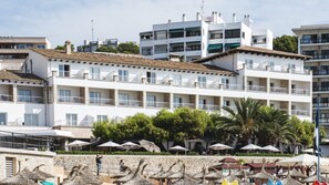 A multi-story hotel with balconies, a pool area with umbrellas, and a stone wall. - Be Live Adults Only La Cala Boutique Hotel (Palma de Mallorca)
