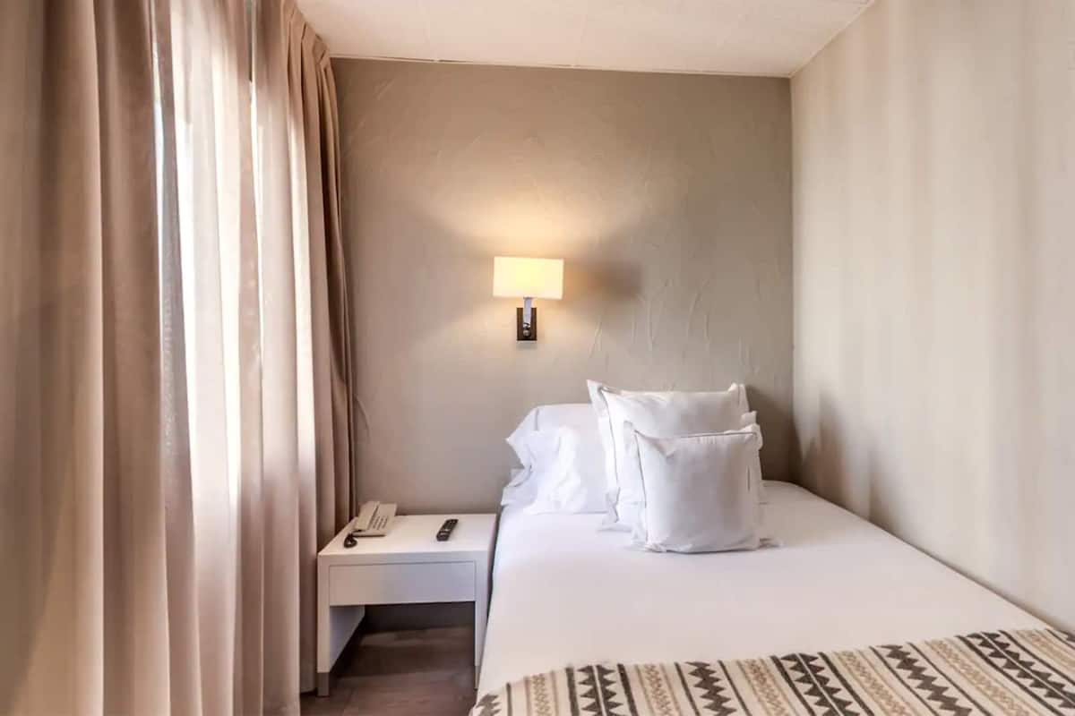 Ein Hotelzimmer mit Bett, Nachttisch mit Lampe und Telefon.