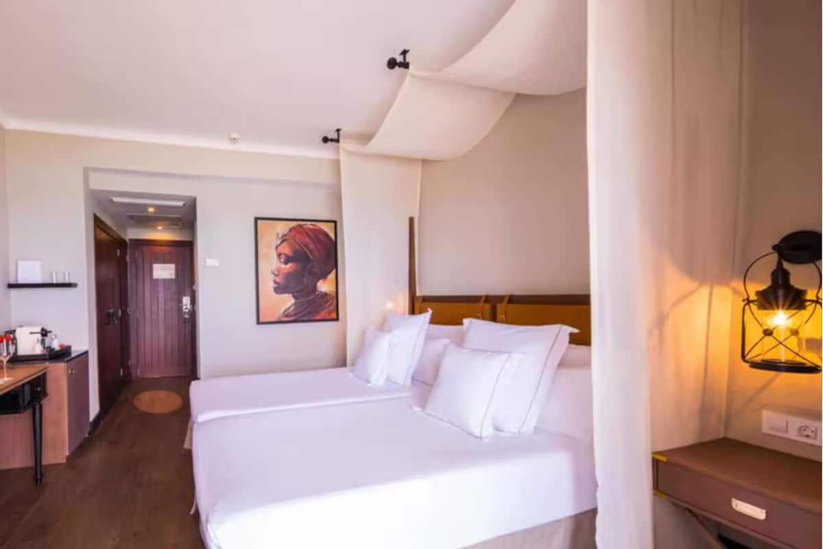 Ein Hotelzimmer mit einem großen Bett, einem Schreibtisch, einem Sessel, einer Lampe und einem Bild an der Wand.