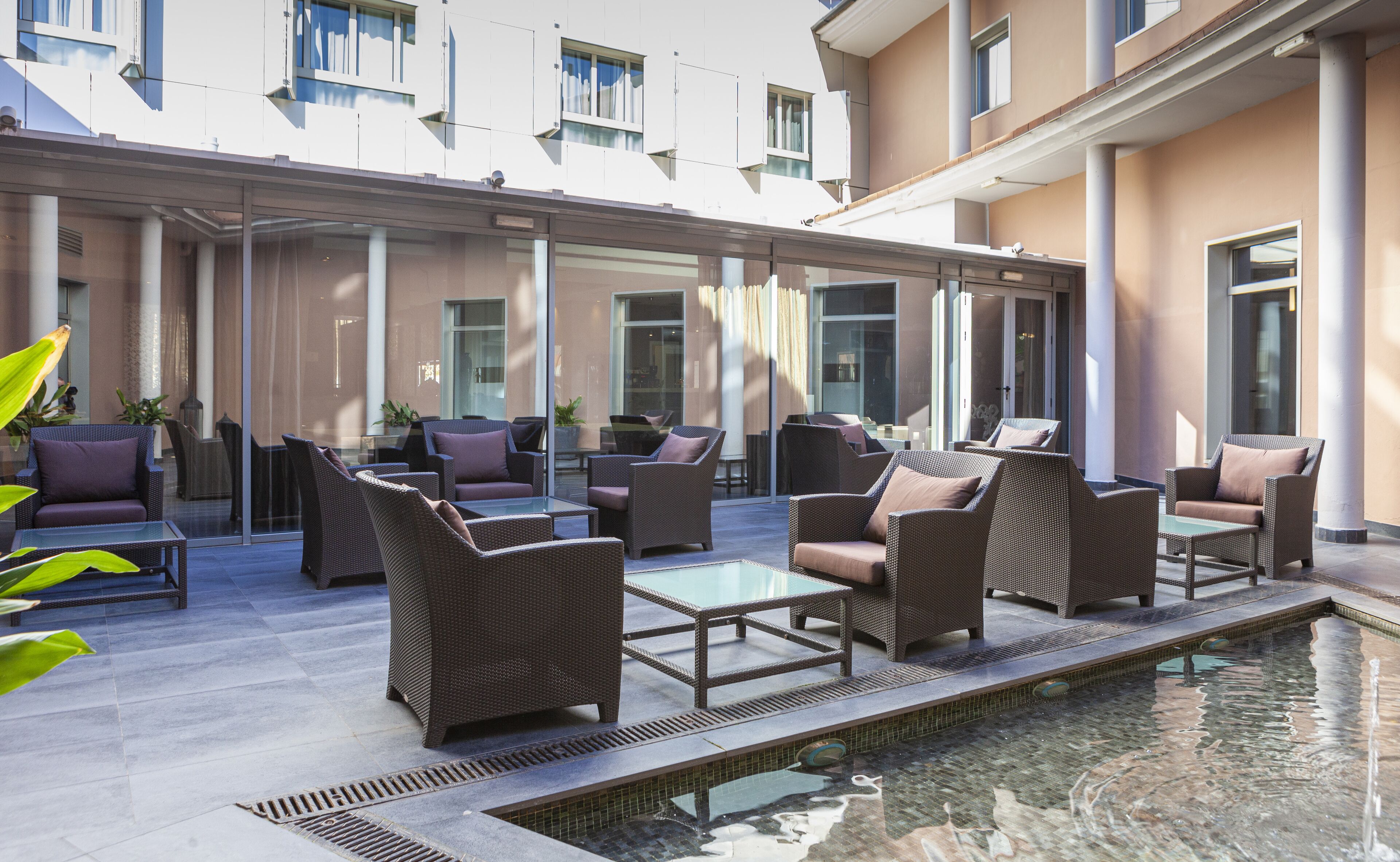 Un área de estar moderna al aire libre con mobiliario de mimbre y una piscina pequeña.