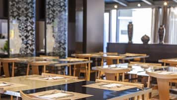 A restaurant with multiple tables and chairs, some with menus and cutlery.