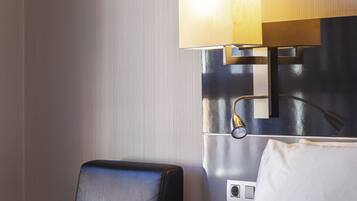 Una habitación de hotel con cama, mesita de noche, lámpara y silla.
