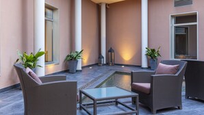 A courtyard with wicker furniture, potted plants, and a central water feature. - Hotel Porcel Torneo (Seville)
