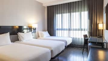 Habitación de hotel con dos camas, un escritorio y una silla.