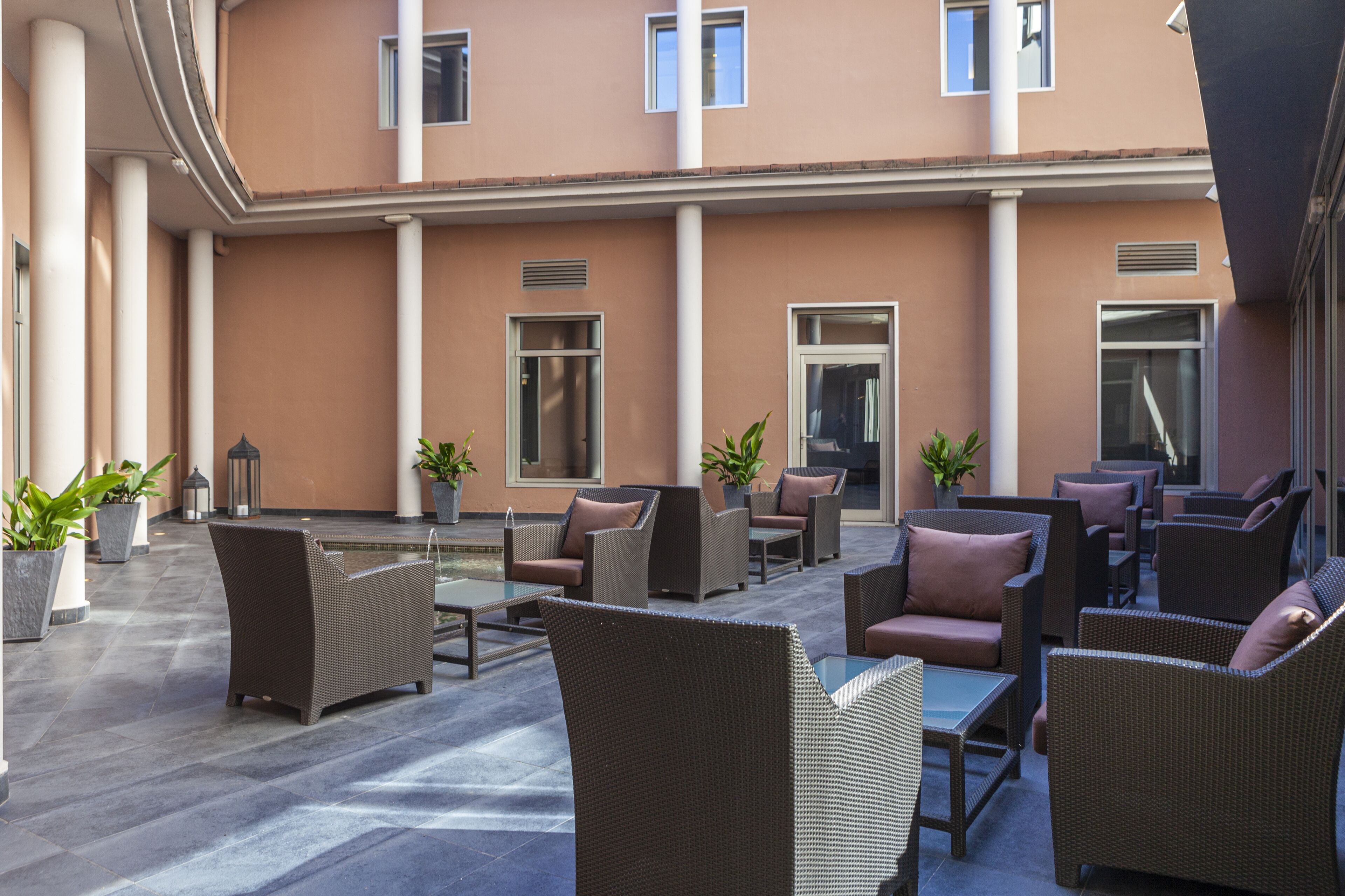 A spacious outdoor seating area with wicker furniture and potted plants.
