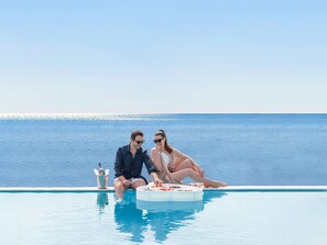 A couple sitting by a pool with a view of the sea. - Atrium Prestige Thalasso Spa Resort & Villas (Rhodes)