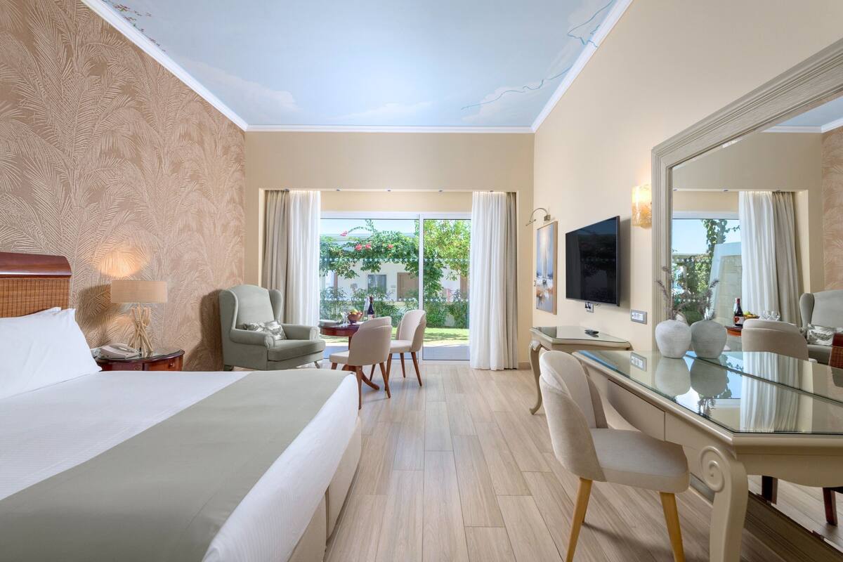 Een hotelkamer met een groot bed, een bureau, een stoel, een televisie en uitzicht op de omgeving.