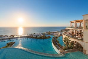A resort with a large infinity pool, a sunlit ocean view, and a covered outdoor seating area. - Atrium Prestige Thalasso Spa Resort & Villas (Rhodes)