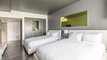 A modern hotel room with two beds, a large mirror, and a small table.
