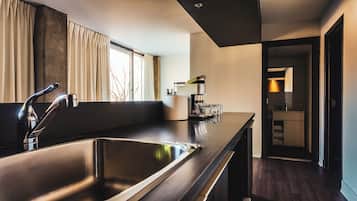 A modern kitchen with a stainless steel sink, a coffee machine, and a window with curtains.